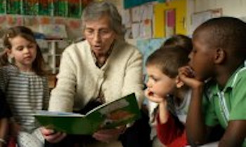 Un adulte lisant un livre à un groupe d'enfant