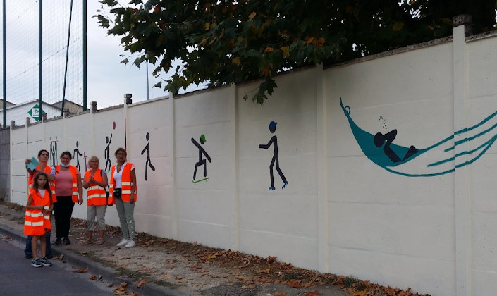 Groupe d'habitants devant le mur du stade horné de dessins