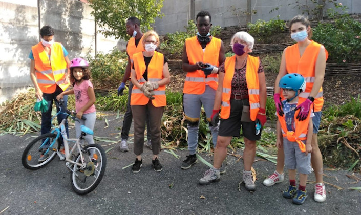 Groupe de personnes (réfugiés, enfants et personnes âgées) posant aprés avoir effectué des plantations.